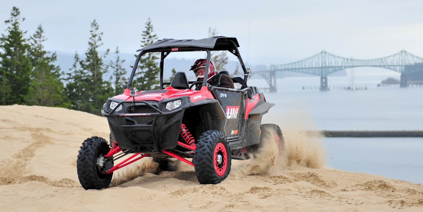 Man riding an ATV in Oregon Dunes by ocean and bridge