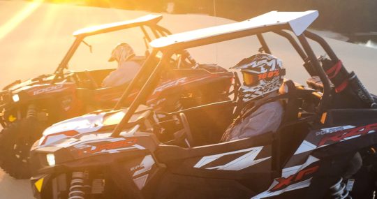 Two guests riding in Can Am Maverick Turbo at sunset