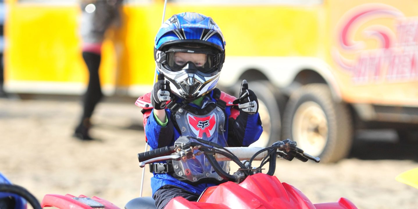 Young boy giving thumbs up on an ATV