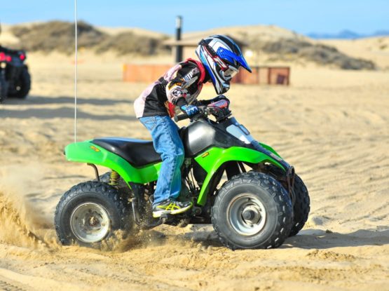 Child riding ATV on sand