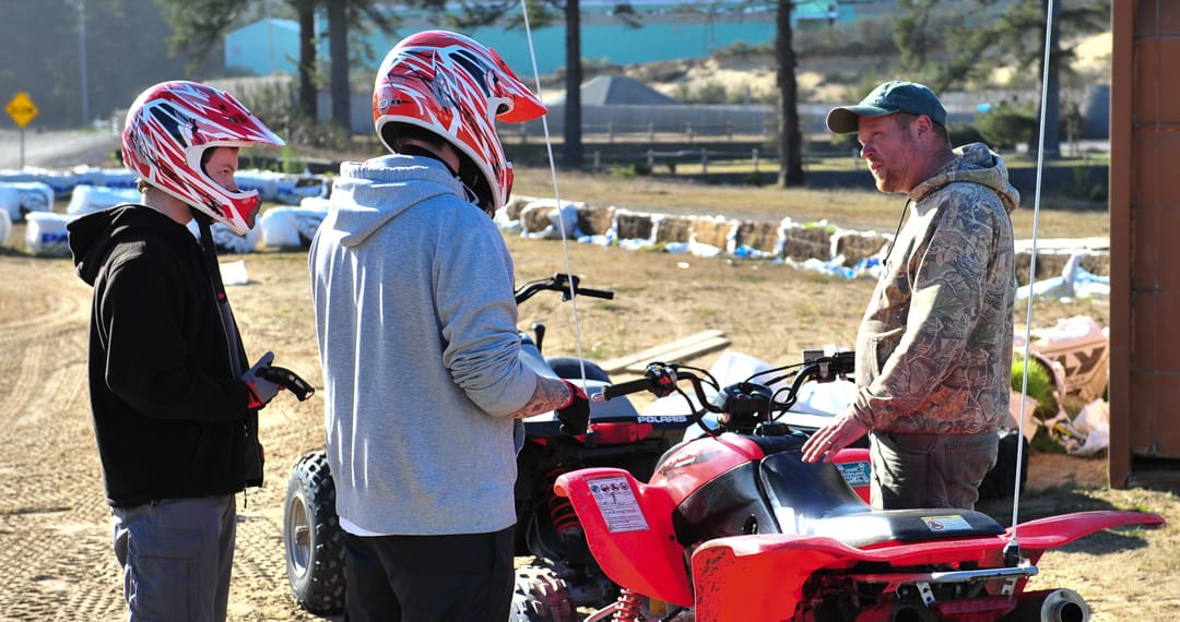 Two guests wearing helmets learning about ATVs