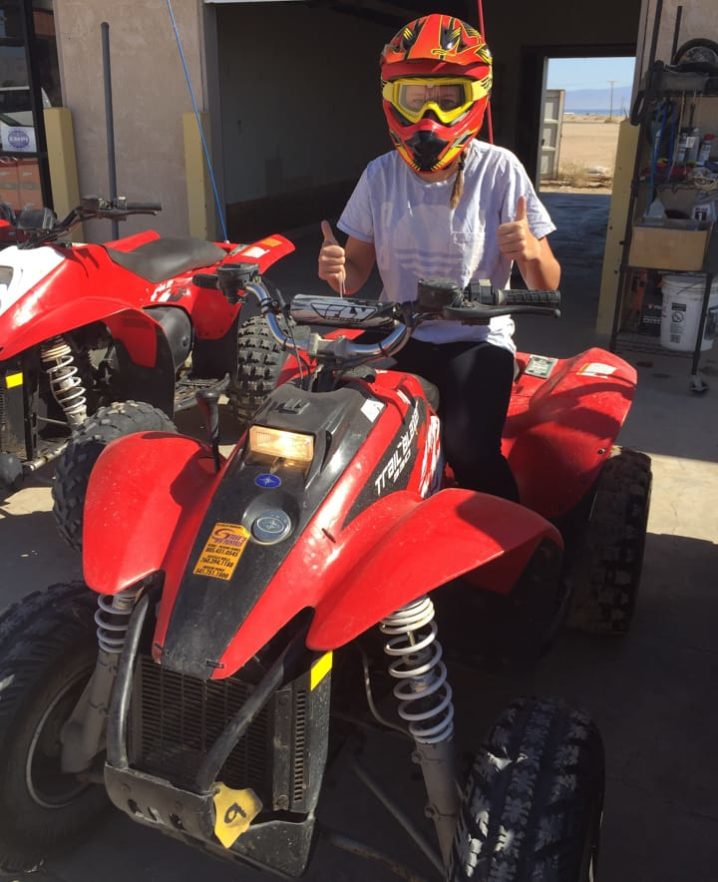 Girl wearing a red helmet and yellow goggles giving a thumbs up