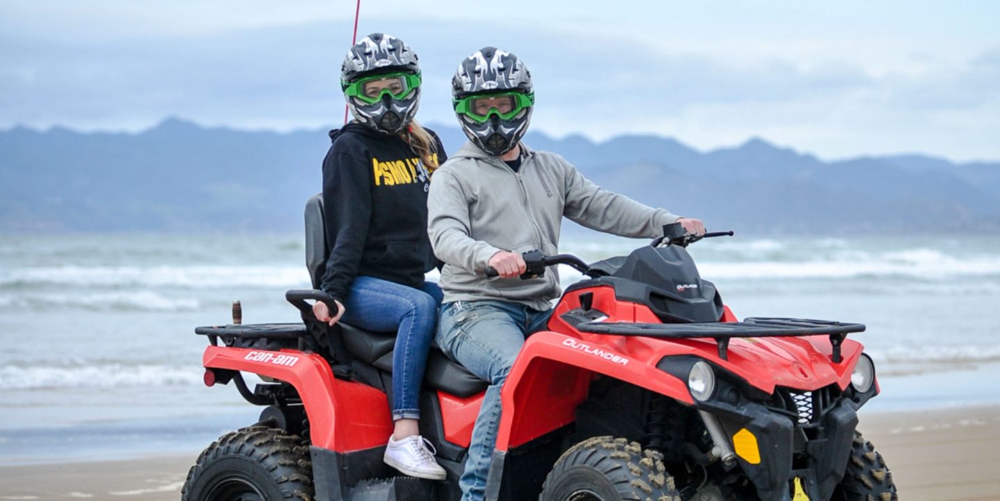 Two women sitting on an ATV at Pismo Beach
