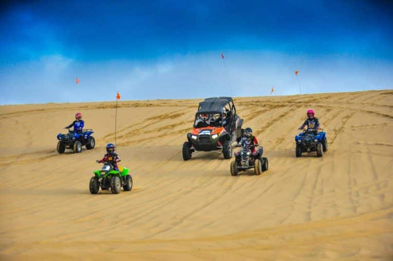 Family riding ATVs downhill in Oregon Dunes