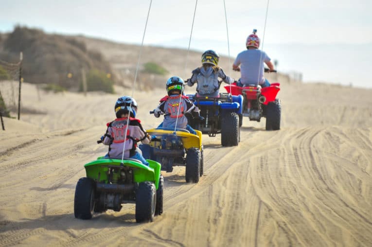 Family riding ATVs at Pismo Beach