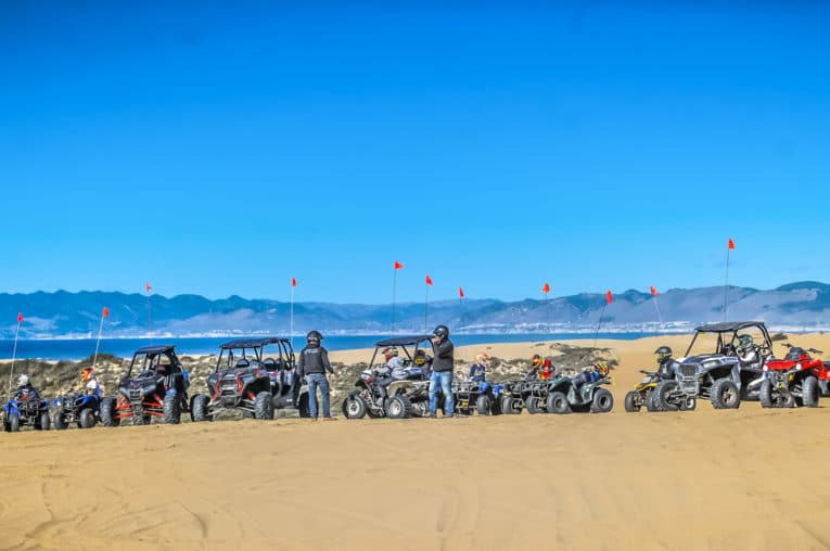 Steve ATV rental vehicles parked at Pismo Beach with guests standing nearby