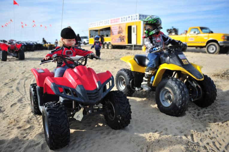 Two children sitting on ATVs at Pismo Beach