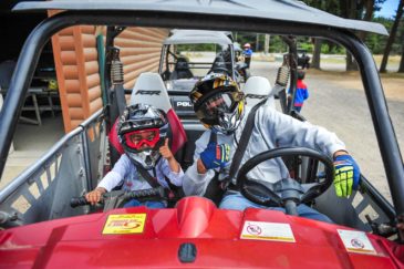 Child and guest sitting in an ATV giving the thumbs up