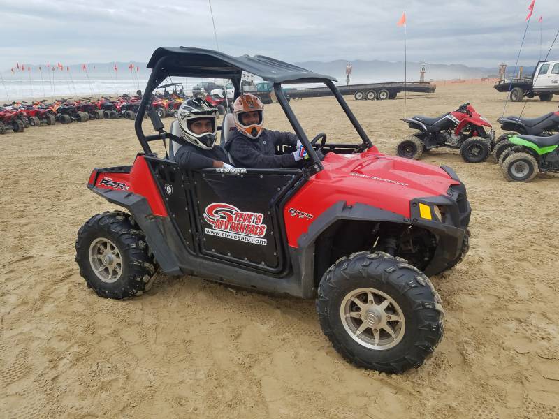  Gast, der einen RZR am Strand fährt